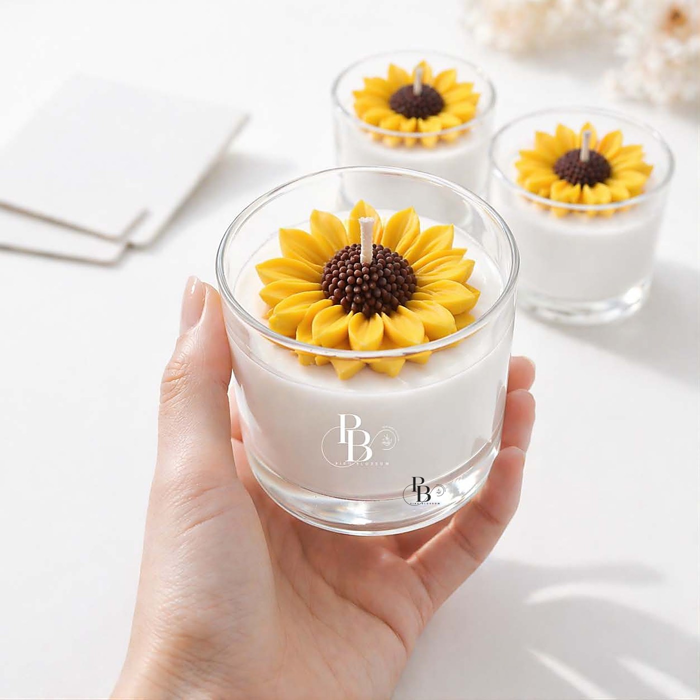 Hand holding a glass jar candle topped with a sunflower, 120ml Murphy Jar, handmade soy wax, Pink Blossom bulk order